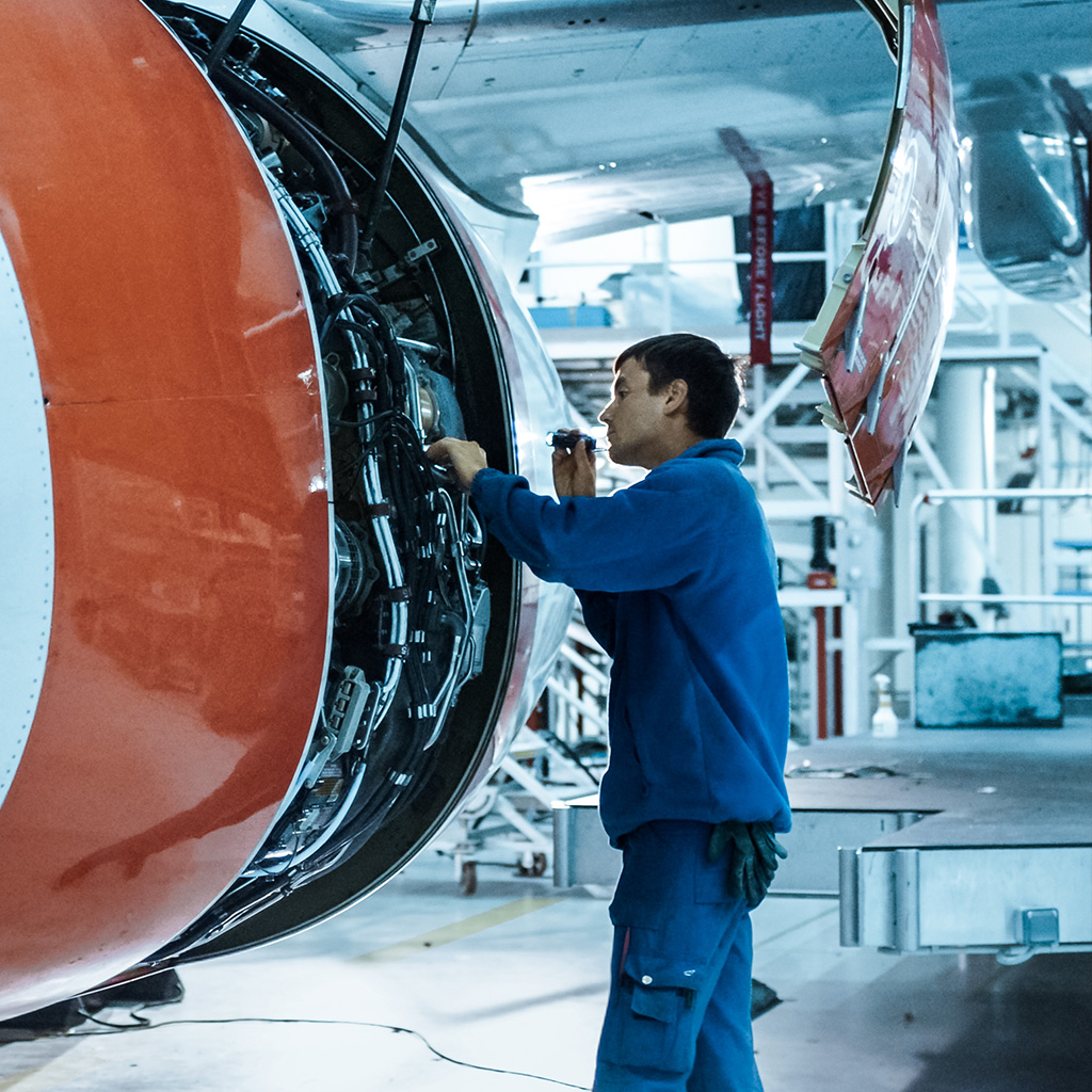 Engineer inspecting aircraft engine, highlighting aviation insurance plans for technical and global risks.