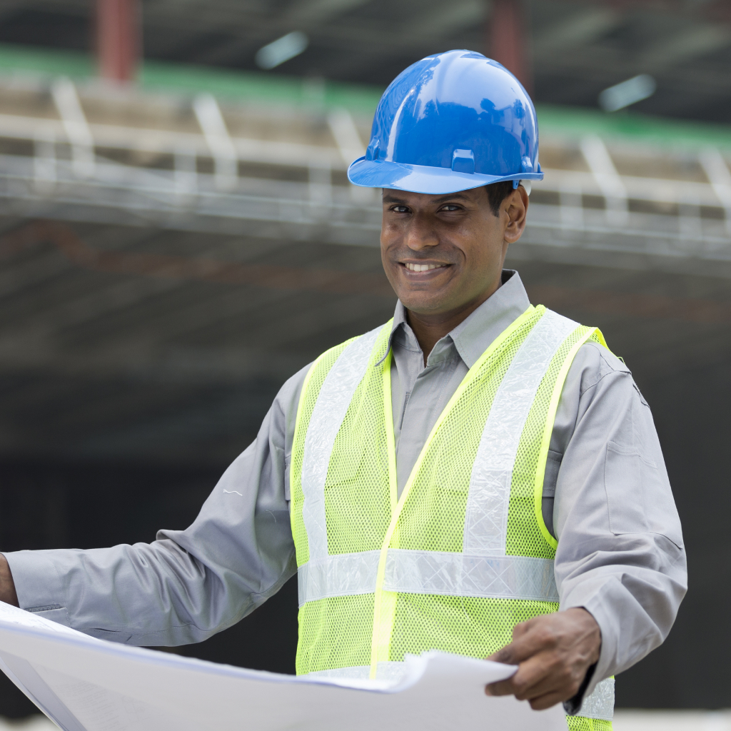 Smiling worker in safety vest and helmet, is a symbol of Sukoon's Abu Dhabi Employee Protect Plan approved by the government