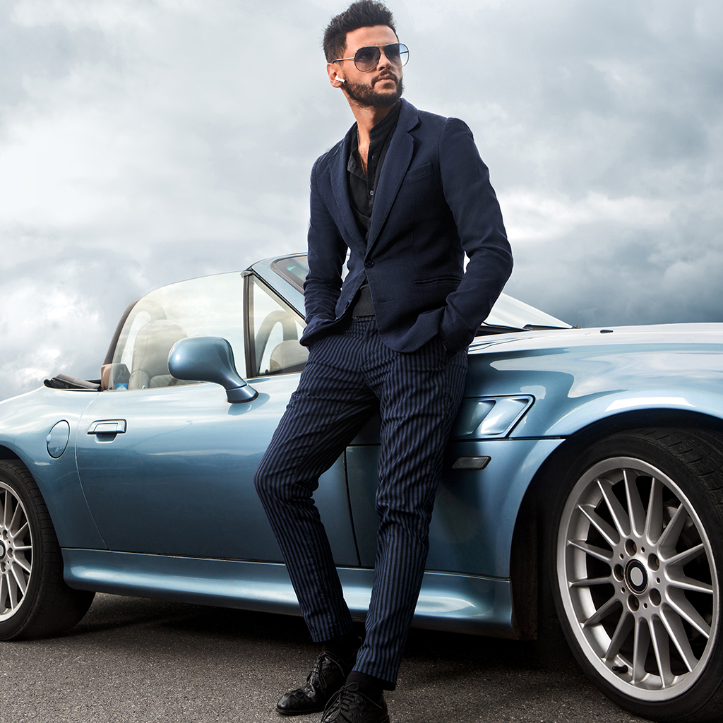 Stylish man in a suit with metallic blue luxury convertible – Privilege Motor Insurance for high-value cars in the UAE